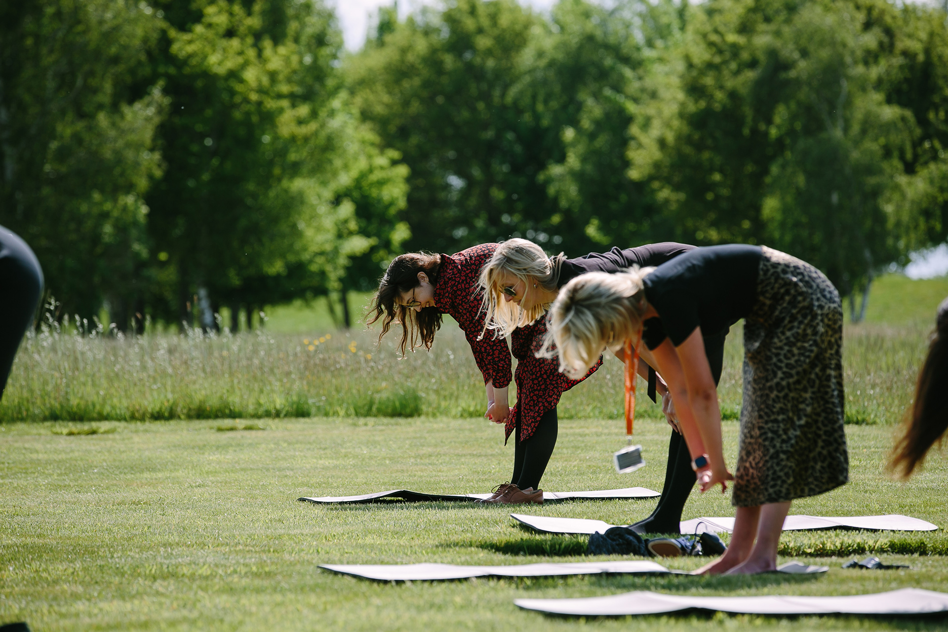 McLaren employees doing outdoor yoga on a grassy field with trees in the background.