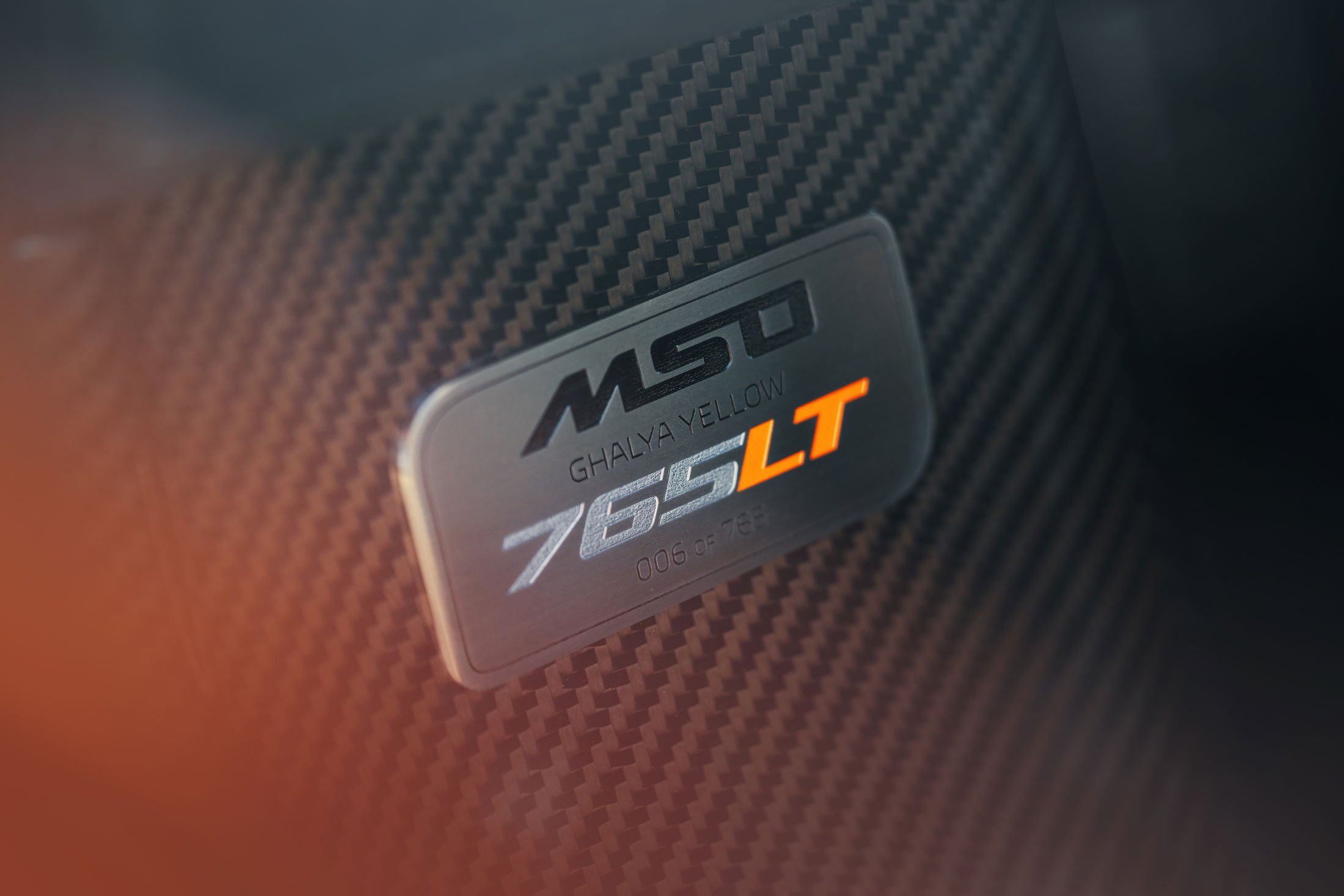 A close-up of a McLaren's MSO (McLaren Special Operations) metal plaque, showing the car is a "Ghalya Yellow 765LT" and specifying its limited edition number, "006 of 765."