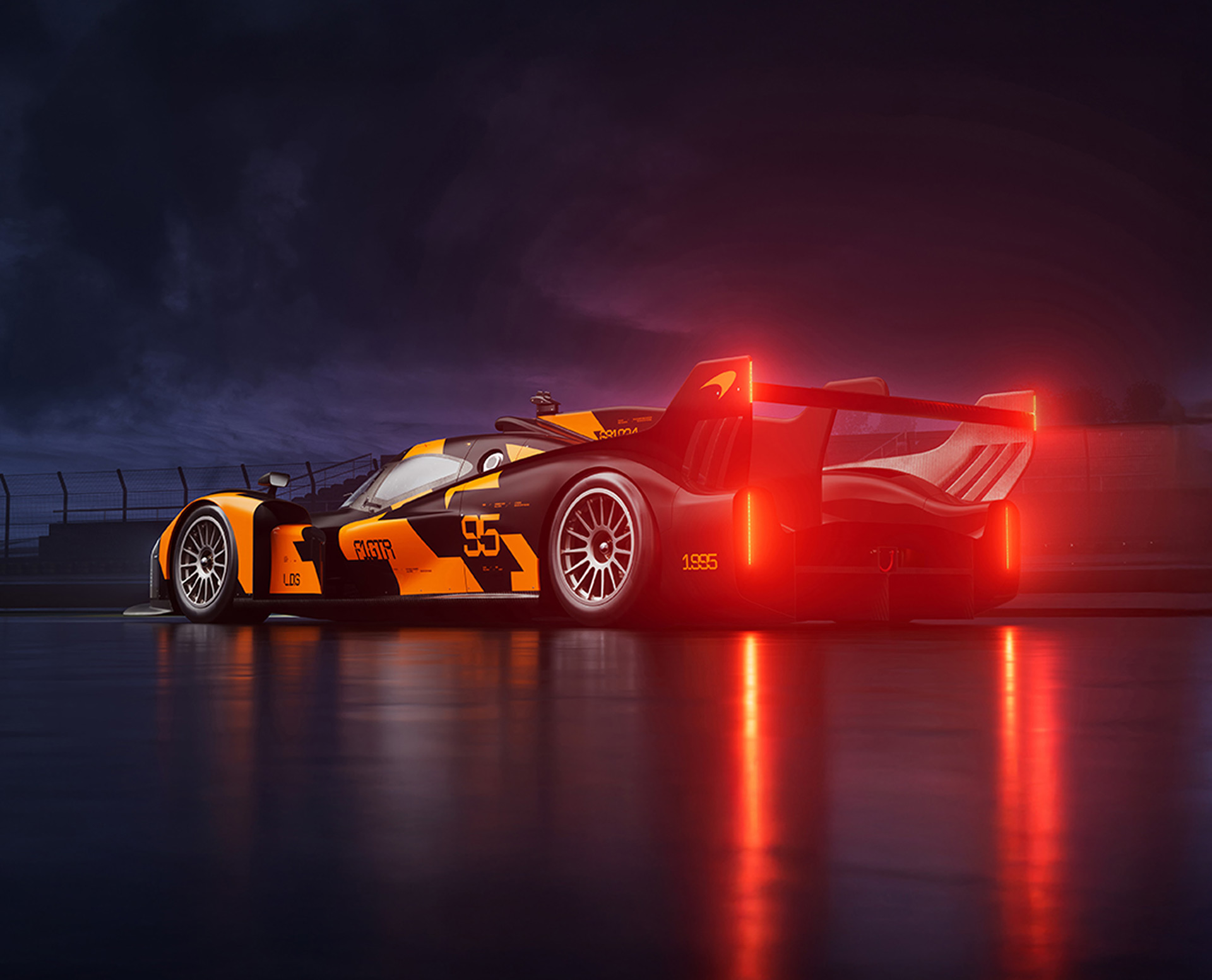 The rear of the McLaren Project Endurance car at night, showcasing its F1 GTR-inspired livery and large illuminated rear wing.