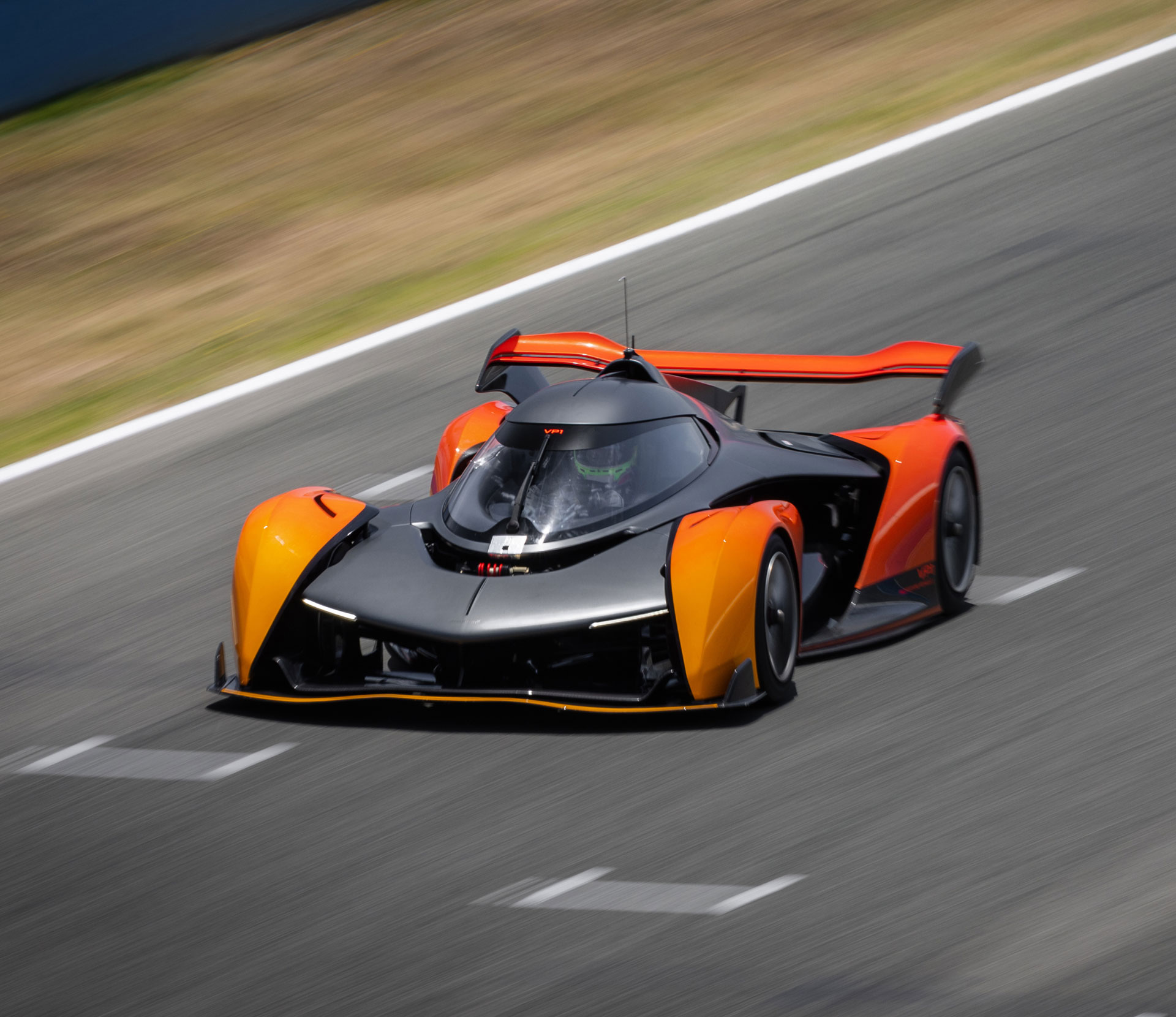 The single-seater McLaren Solus GT track-only car driving at high speed on a circuit, highlighting its aerodynamic design and orange livery.